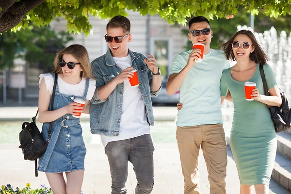 Young people walking around the city. Stylish friends together having fun. Group of people drinking coffee and talking.