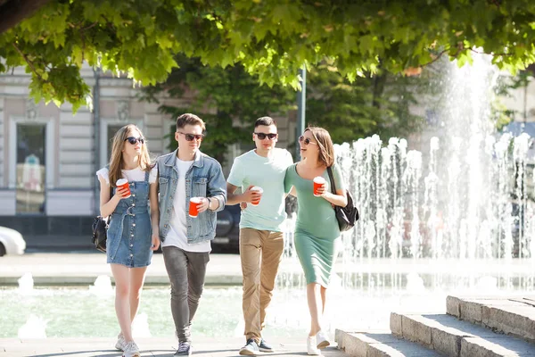 Young people walking around the city. Stylish friends together having fun. Group of people drinking coffee and talking.