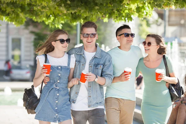 Young people walking around the city. Stylish friends together having fun. Group of people drinking coffee and talking.