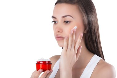 Yüz kremi uygulayan genç çekici kadının closeup portresi. Kadın nemlendirici yüz kremi ile bir kavanoz tutarak.