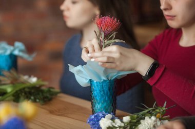 Çiçek maser sınıfı. Taze çiçeklerle çiçek kompozisyonu yapan kadınlar.