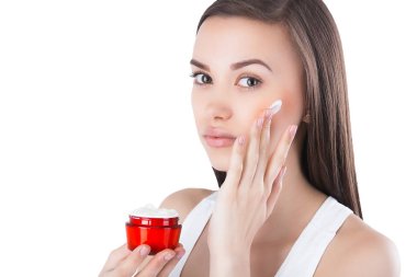 Yüz kremi uygulayan genç çekici kadının closeup portresi. Kadın nemlendirici yüz kremi ile bir kavanoz tutarak.