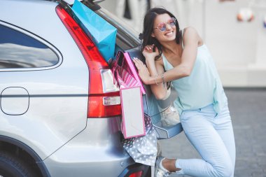 Perakende satışını arabaya koymaya çalışan kadın. Satın alma için yeterli alan yok. Alışveriş kızı. Alışverişte Alışverişkolik.