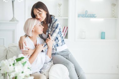 Olgun anne ve yetişkin kızı birlikte. İçerideki kadınlar portresi. Orta yaş kadın ve kızı evde kanepede oturan.