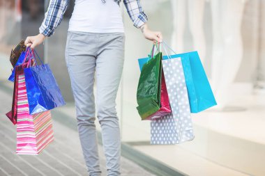 Alışveriş merkezinden alışveriş yapan çekici genç bir kadın. Marketin yanında alışveriş torbaları tutan bir kadın. Alışveriş yapan çekici bir kadın..