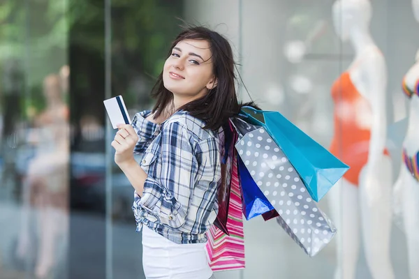 Young attractive woman shopaholic walking trough shopping mall. Lady holding shopping bags near the showcase. Attractive woman doing shopping.