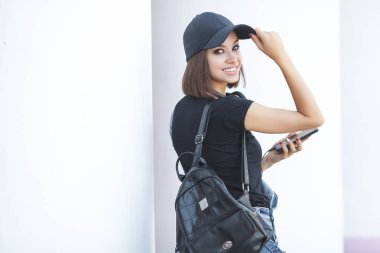 Araçlarla tarafsız arka planda olan kadın. Modern gençlik. Akıllı telefonda müzik dinleyen ve yazan genç kadın.