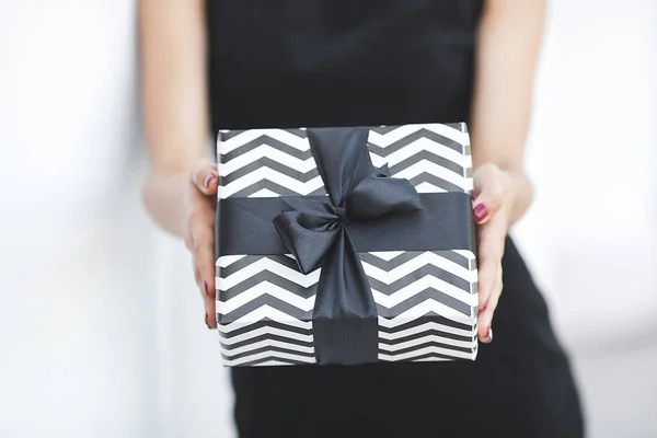 Present box. Black gift. Woman holding black and white presents.