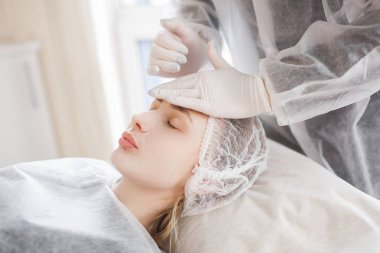 Usta müşterisi için kozmetik bir işlem yapıyor. Cilt bakımı. Kadın yüz bakımı prosedürü uyguluyor.