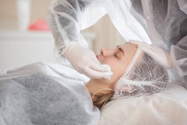 Usta müşterisi için kozmetik bir işlem yapıyor. Cilt bakımı. Kadın yüz bakımı prosedürü uyguluyor.