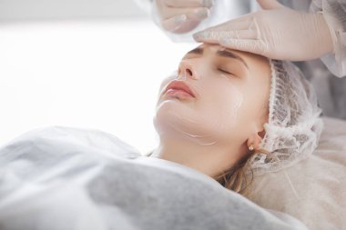 Usta müşterisi için kozmetik bir işlem yapıyor. Cilt bakımı. Kadın yüz bakımı prosedürü uyguluyor.