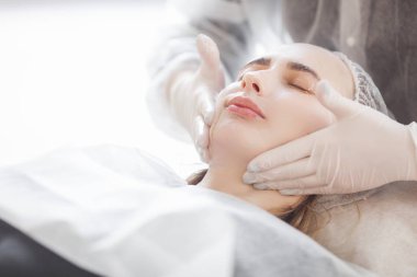 Usta müşterisi için kozmetik bir işlem yapıyor. Cilt bakımı. Kadın yüz bakımı prosedürü uyguluyor.