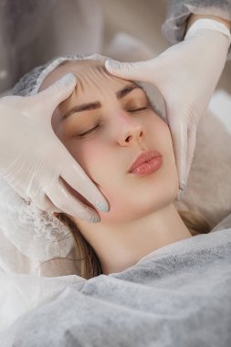 Usta müşterisi için kozmetik bir işlem yapıyor. Cilt bakımı. Kadın yüz bakımı prosedürü uyguluyor.