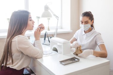 Manikürcü kuaförde manikür yapıyor. Usta servising müşterisi. Çivi bakım prosedürü.