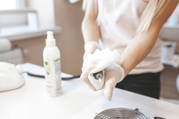 Manicurist cleaning her place to service a new client. Sterilizing salon table to prevent infection.