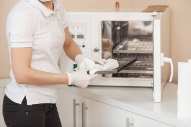 Manikürcü otoklav veya fırında onu araçları sterilize. Salonda usta dezenfeksiyon için onun aletleri hazırlanıyor.