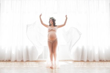 Tarafsız bir geçmişe sahip güzel hamile bir kadın. Beklenen yakın çekim resmi. Pastel arka plan da gelecekteki anne portresi.