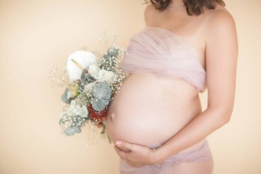 Tarafsız bir geçmişe sahip güzel hamile bir kadın. Beklenen yakın çekim resmi. Pastel arka plan da gelecekteki anne portresi.