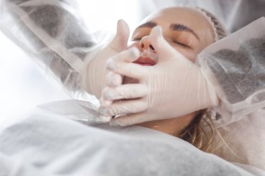 Usta müşterisi için kozmetik bir işlem yapıyor. Cilt bakımı. Kadın yüz bakımı prosedürü uyguluyor.