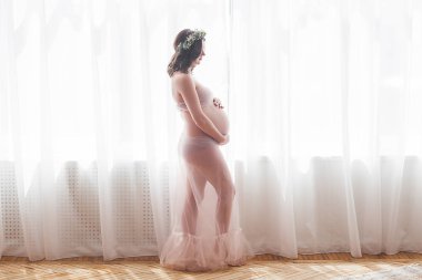 Tarafsız bir geçmişe sahip güzel hamile bir kadın. Beklenen yakın çekim resmi. Pastel arka plan da gelecekteki anne portresi.