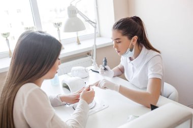 Manikürcü kuaförde manikür yapıyor. Usta servising müşterisi. Çivi bakım prosedürü.