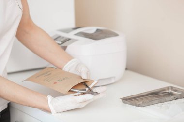 Manikürcü otoklav veya fırında onu araçları sterilize. Salonda usta dezenfeksiyon için onun aletleri hazırlanıyor.