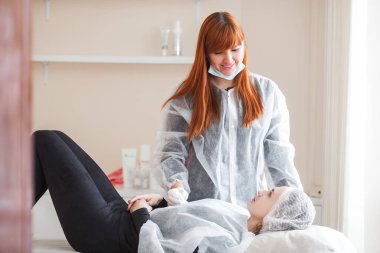 Usta müşterisi için kozmetik bir işlem yapıyor. Cilt bakımı. Kadın yüz bakımı prosedürü uyguluyor.