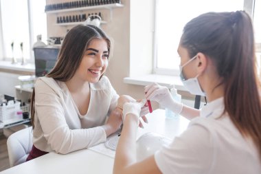 Manikürcü kuaförde manikür yapıyor. Usta servising müşterisi. Çivi bakım prosedürü.