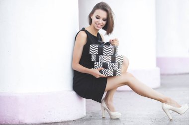 Güzel, genç, esmer bir kadın, elinde siyah cuma hediyeleri tutuyor. Tarafsız beyaz arka planda bir kadın elinde kurdeleli kara kutular tutuyor.