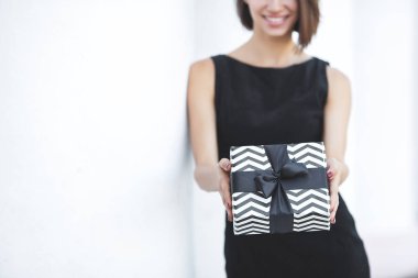 Güzel, genç, esmer bir kadın, elinde siyah cuma hediyeleri tutuyor. Tarafsız beyaz arka planda bir kadın elinde kurdeleli kara kutular tutuyor.