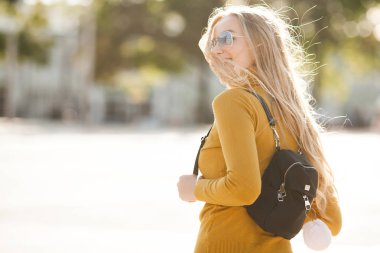 Çekici, genç, sarışın kadın portresi. Sonbahar güneşinin arka planında açık havada bir kadın. Sonbaharda neşeli bir kadın portresi..