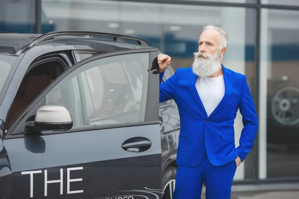 Old stylish man in car sales center. Mature man choosing new automobile.