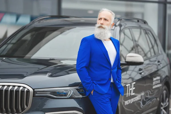 Old stylish man in car sales center. Mature man choosing new automobile.