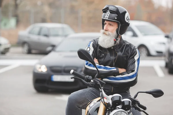 Old stylish man driving the motorcycle. Brutal male.