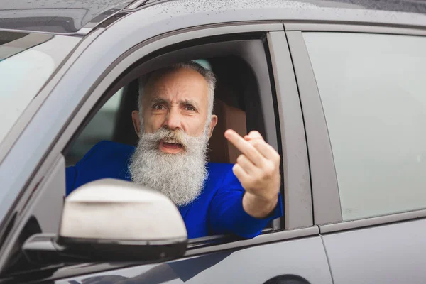 Old brutal man in the car. Angry driver