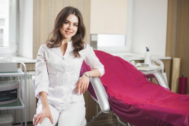 Genç, çekici bir kadın doktor. Klinikte üniforma giyen kadın portresi. Tıbbi ekipmanlı bir doktor. Salonunda kozmetik uzmanı.