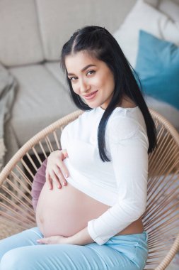 Çocuk bekleyen çekici genç bir kadın. Hamile bir kadın. İçerideki kadın karnını kucaklıyor..