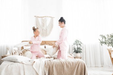 Genç aktif anne ve küçük kızı evde pijama giyerek eğleniyorlar.