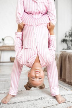 Genç aktif anne ve küçük kızı evde pijama giyerek eğleniyorlar.