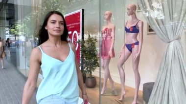 Vitrinin yanında alışveriş torbaları taşıyan çekici bir kadın..