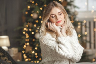 Noel arkaplanındaki çekici sarışın genç kadının yakın plan portresi.