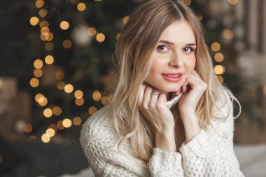 Noel arkaplanındaki çekici sarışın genç kadının yakın plan portresi.