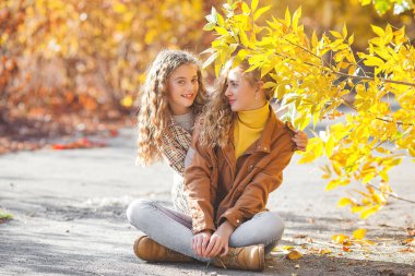 Sonbahar arka planında iki kız birlikte dışarıda.