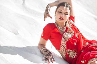 Tarafsız arka planda güzel bir Hintli kadın. Mehendi desenli sarili bayan.