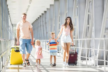 Havaalanında bavulları gezen mutlu bir aile.