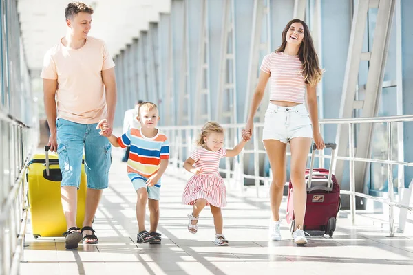 Havaalanında bavulları gezen mutlu bir aile.