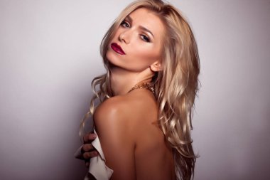 Güzel kadın manken beyaz elbise gri arka plan üzerinde poz 