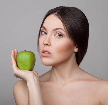 Doğal makyaj gri arka plan üzerinde yeşil elma ile poz olan kadın portresi 