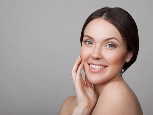 Portrait of young sensitive woman with natural makeup on grey background 