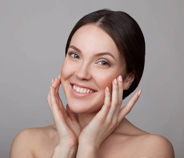 Portrait of young sensitive woman with natural makeup on grey background 